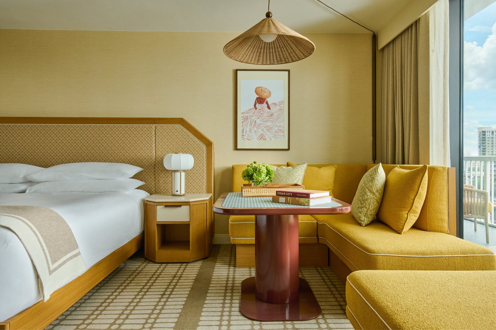Hotel Cala guestroom with a bed, mustard-yellow corner seating and balcony window.