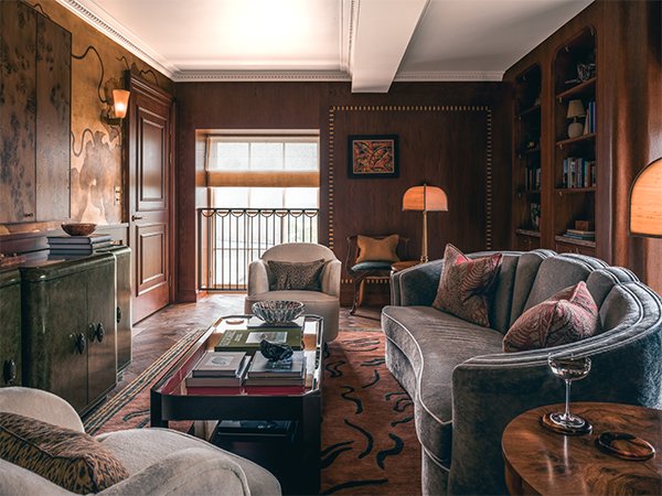 Wood-panelled sitting room with curved sofa, armchairs and a coffee table in the Gleneagles Tower Suite.