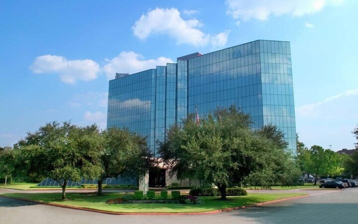 Hilton Houston Westchase exterior with glass-fronted towers, trees and entrance driveway