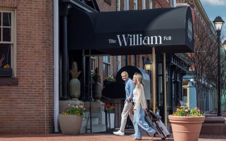 Two guests with luggage outside The William Fell Baltimore, Tapestry Collection by Hilton