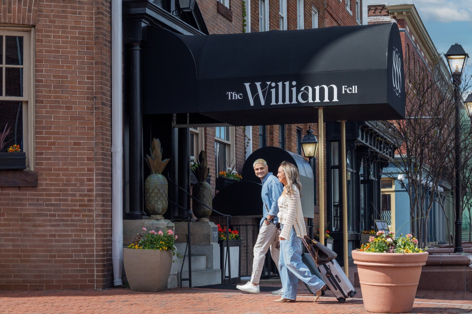 Two guests with luggage outside The William Fell Baltimore, Tapestry Collection by Hilton