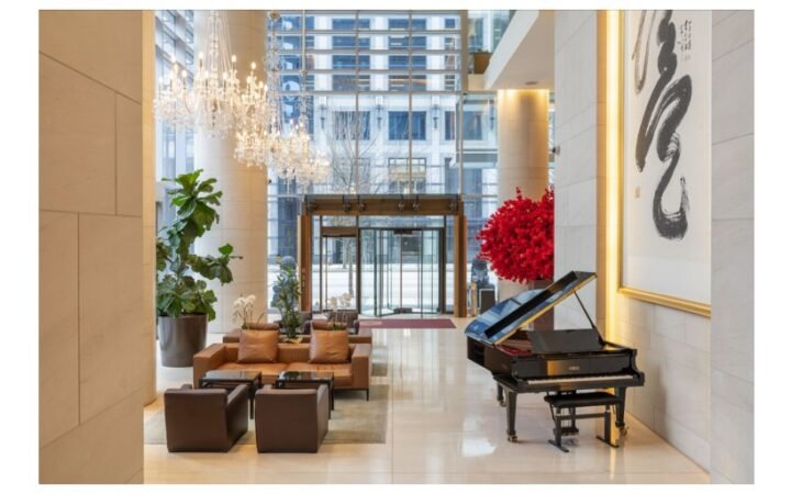 Lobby at Hyatt Vancouver Downtown Alberni with seating, chandeliers, a grand piano and tall windows.