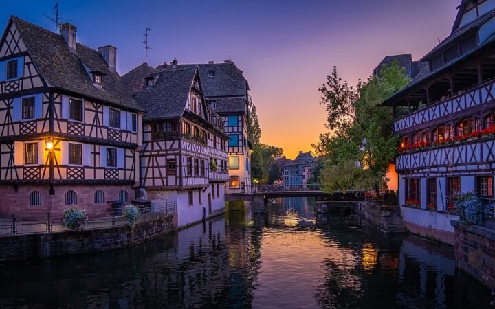 Half-timbered buildings beside a canal in Strasbourg’s Petite France district at dusk