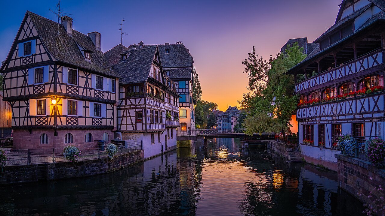Half-timbered buildings beside a canal in Strasbourg’s Petite France district at dusk
