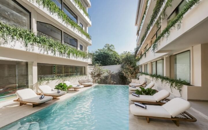 Pool courtyard framed by planted balconies and loungers at UMI Resort in Uluwatu, Bali.